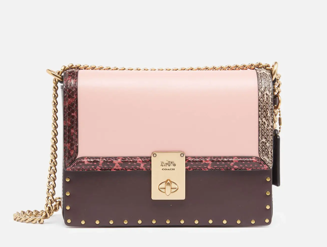 Coach 与 J.Lo 合作推出的“Hutton”单肩包将桑椹绒面革和精致的淡粉色皮革与真正的蛇皮饰边融为一体
